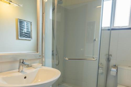 努沃勒埃利耶The Tapherini Bungalow的白色的浴室设有水槽和淋浴。