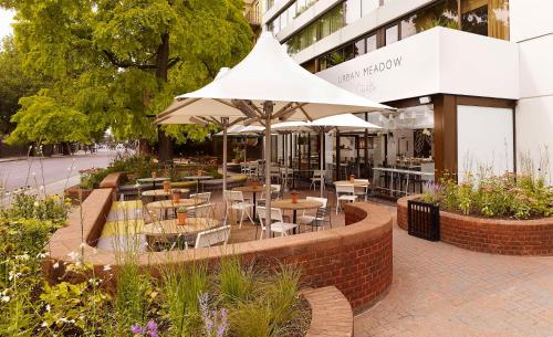 伦敦伦敦海德公园希尔顿逸林酒店的一间带桌椅和遮阳伞的餐厅