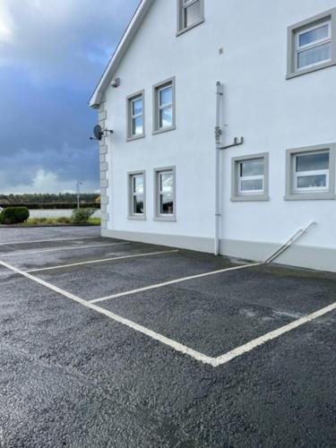 科尔雷恩New Lisnagalt Lodge的一座白色的建筑,旁边设有停车场