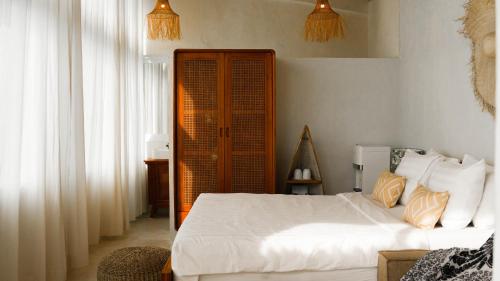 乌鲁瓦图Ulunia的卧室配有白色的床和木制橱柜。
