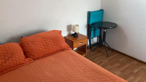 拉塞雷纳BELLAS Y COMODAS HABITACIONES EN LA SERENA的一间卧室配有一张带橙色棉被和桌子的床