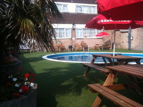 大雅茅斯维多利亚酒店的一个带两张野餐桌和一把红色遮阳伞的游泳池