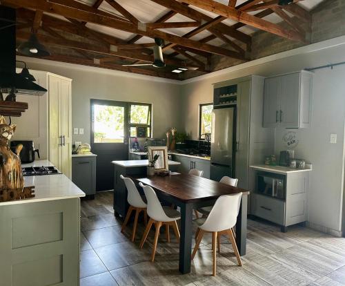 理查兹湾Palm Tree Cottage Felixton的厨房配有木桌和白色椅子