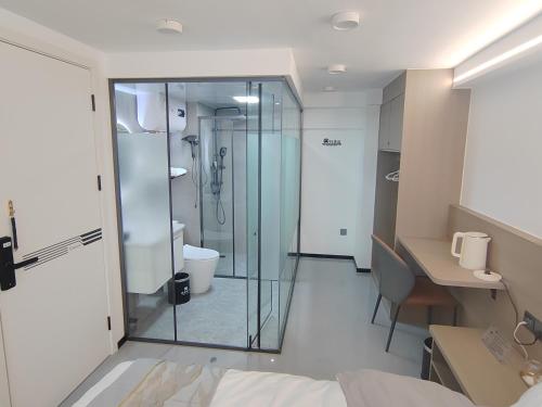 厦门南风吹梦民宿(厦门北站店)的一间带玻璃淋浴的浴室和一张书桌