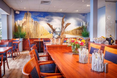 海滨诺德韦克明星酒店的一间带桌椅和壁画的餐厅