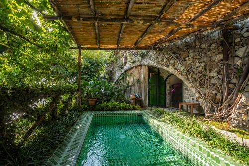波西塔诺特弗维耶别墅酒店的一座带石墙的花园内的室外游泳池