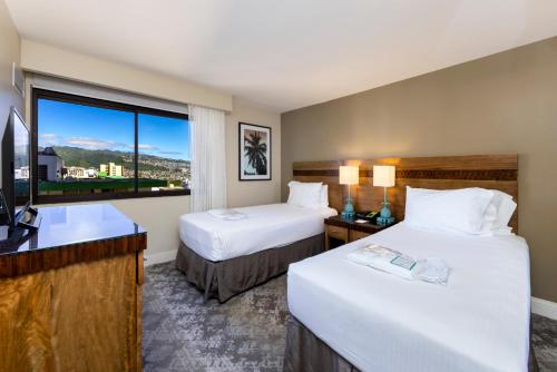 檀香山Ocean Front Spectacular Condo的酒店客房设有两张床和窗户。