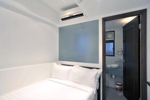 香港名樂居 By The Park的小房间设有一张带白色枕头的床