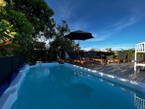 卡塔赫纳Los Patios Hostel的一个带椅子和遮阳伞的游泳池