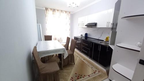 奇姆肯特3х комнатная квартира в жилом комплексе ОТАУ сити的厨房配有桌椅和水槽。
