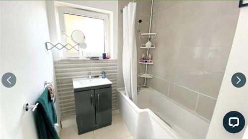 利夫斯登格林4 bedroom property which sleeps 8 very close to the Harry Potter studio and Watford junction的浴室配有水槽、淋浴和浴缸。