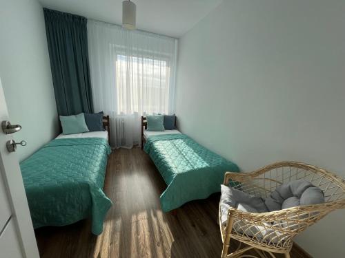 什切青Apartament Słoneczne Szczecin的客房设有两张床、一把椅子和窗户。