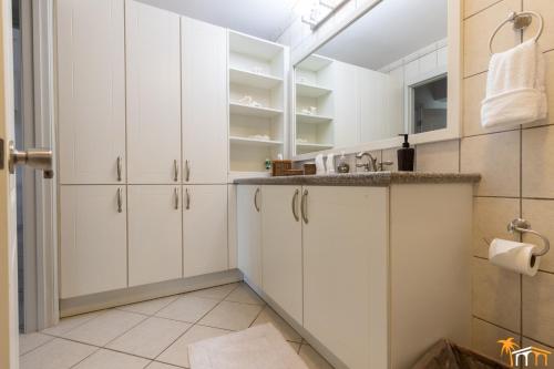 棕榈滩豪华海景太阳之地别墅的白色的厨房配有白色橱柜和水槽