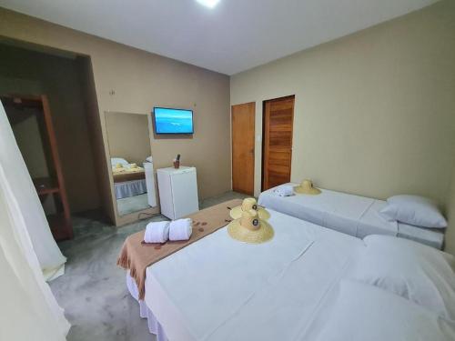 杰里科科拉Deu Praia Pousada的客房设有两张带毛巾的床和电视。