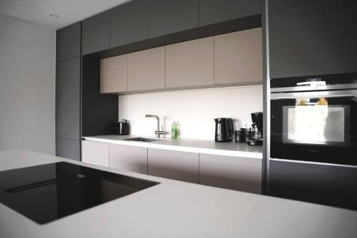 卢森堡Beautiful Stylish 2BR Apartment in Kirchberg的厨房配有白色橱柜和炉灶烤箱。