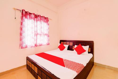 ChinhatOYO Flagship Shine Hotel的一间卧室配有一张带红色枕头的床和一扇窗户