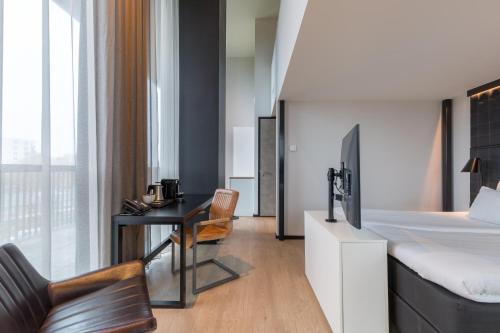 格罗宁根Leonardo Hotel Groningen的一间卧室配有一张床和一张书桌及电视