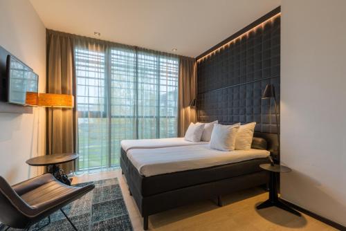 格罗宁根Leonardo Hotel Groningen的配有一张床和一把椅子的酒店客房