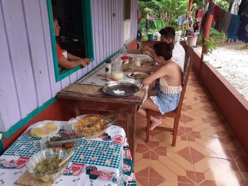 马瑙斯POUSADA CANTO DOS PASSÁROS的坐在餐桌旁吃食物的男人和女人