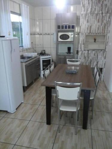 马沙蒂纽Cabana econômica com 2 quartos的厨房配有木桌和白色冰箱。