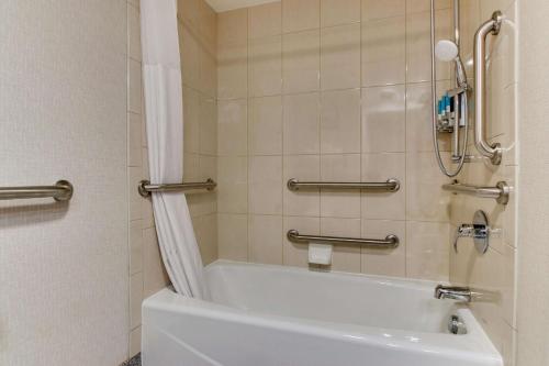 埃德蒙逊圣路易斯机场梨树酒店的浴室配有白色浴缸和淋浴。