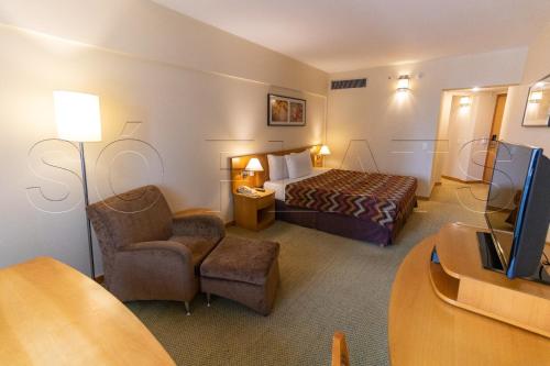 巴鲁埃里Hotel & Residência Alphaville的配有一张床和一把椅子的酒店客房