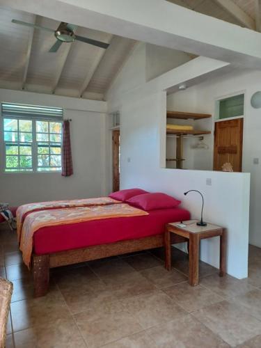 TanetaneMango Garden Cottages的一间卧室配有一张带红色枕头的床和一张桌子