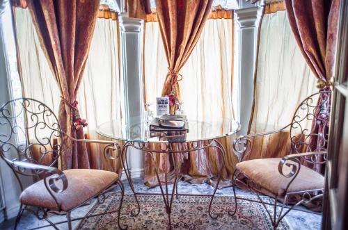 盐湖城周年庆旅馆 - 南寺的玻璃桌和两把椅子,位于窗帘的房间