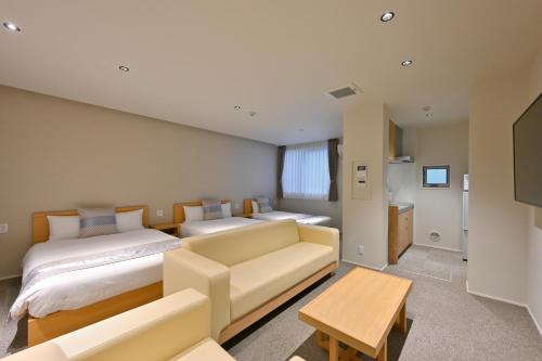 广岛GRAND BASE Hiroshima Peace Memorial Park的一间带两张床和一张沙发的客厅
