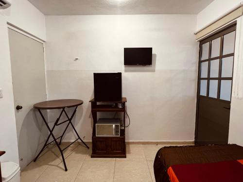 梅里达Habitación independiente al Norte de Mérida的一间墙上配有电视和一张桌子的房间