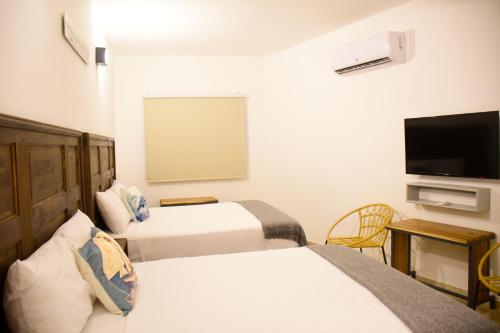 圣塔芭芭拉-山美纳Hostal Marina Samana的酒店客房设有两张床和一台平面电视。