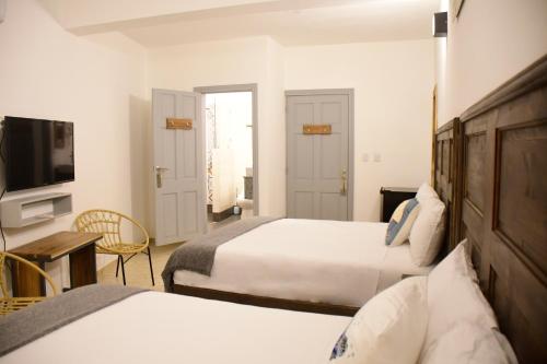 圣塔芭芭拉-山美纳Hostal Marina Samana的酒店客房设有两张床和电视。
