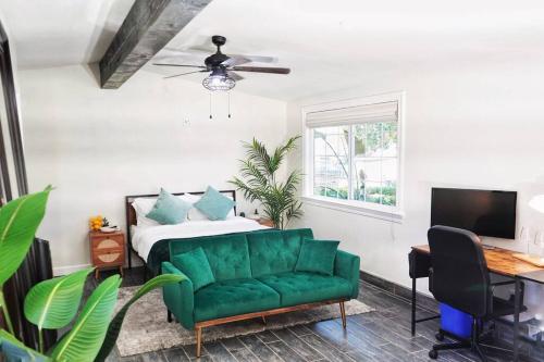 圣何塞Casita Hosum: Modern WFH Garden Suite w/ Gazebo Outdoor Kitchen & BBQ的一间卧室配有绿色的沙发和一张床