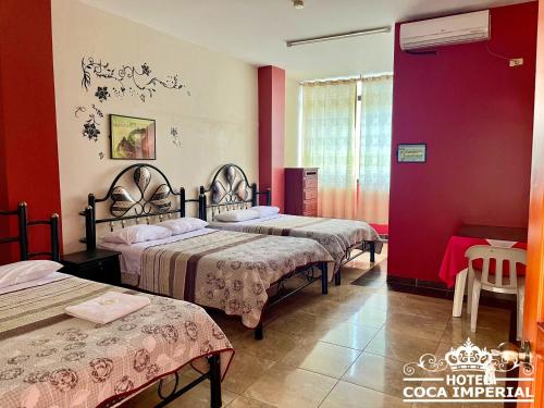 弗朗西斯科德奥雷利亚纳港Hotel Coca Imperial的一间设有三张床和红色墙壁的房间