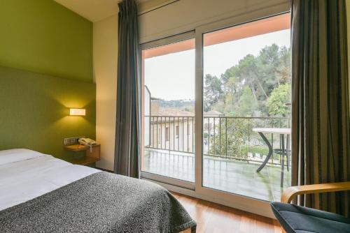 La Pobla de Claramunt罗伯特酒店的一间卧室设有一张床和一个阳台的大窗户