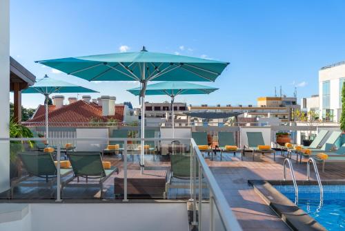 丰沙尔马德拉酒店的一个带椅子和遮阳伞的庭院和一个游泳池