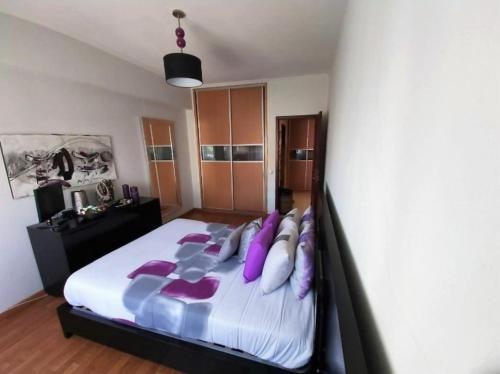 拉夫拉Apartamento frente ao mar的一间卧室配有一张带紫色枕头的大床