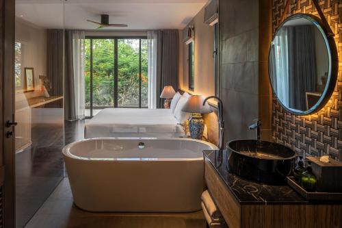 查龙Noku Phuket的带浴缸、床和镜子的浴室