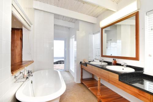 阿多祖伯格山村酒店的浴室配有2个盥洗盆、浴缸和大镜子