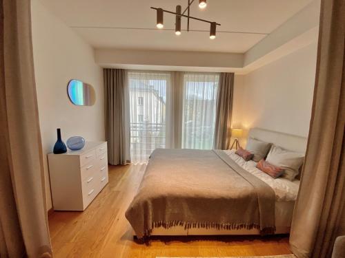 塔林Cozy Home Apartment - Tallinn City Center的一间卧室配有一张床、一个梳妆台和一扇窗户。