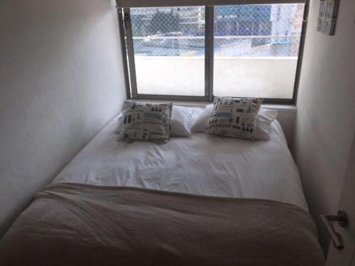 圣地亚哥Kennedy Premium Apartments Colorado的窗户间内的一张带两个枕头的床