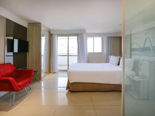 巴西利亚巴西利亚利德美居酒店的酒店客房,配有一张床和一张红色椅子