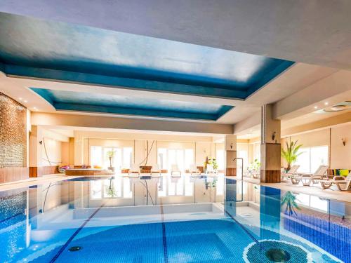拉茨瓦维采拉茨瓦维采多斯洛尼采美居酒店、会议中心及水疗中心的一座拥有蓝色天花板的大型游泳池