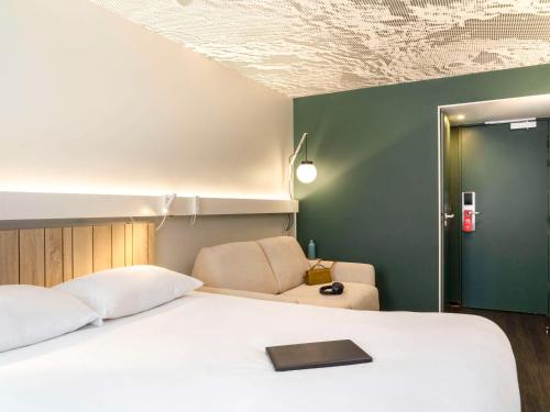 巴黎ibis Paris Nation Davout的卧室配有白色的床和绿色的墙壁