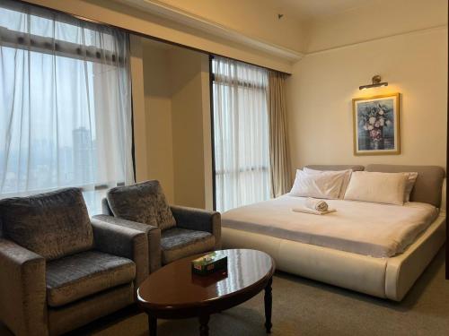 吉隆坡RESORT SUITES AT BARJAYA TIMES SQUARE kL的配有一张床和一把椅子的酒店客房