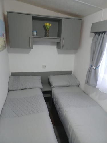 坦伯利8 berth caravan Turnberry Holiday Park的小型客房 - 带2张床和窗户
