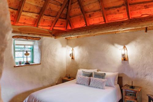 RusheenyPatsys Cottage 415的卧室设有白色的床和木制天花板。