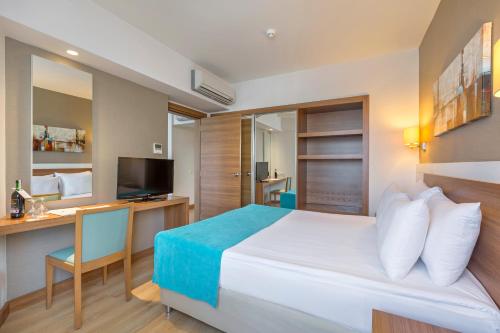 拉瑞拉拉大公园酒店的酒店客房配有一张床、一张书桌和一台电视。