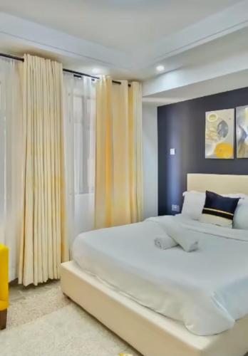 内罗毕The place rich的卧室配有一张白色大床和黄色窗帘