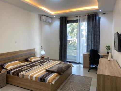 达喀尔CHEZ CODOU FANN - POINT E的一间卧室配有一张床、一张书桌和一个窗户。